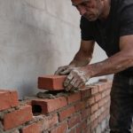 Rebuilding Life After Addiction (One Brick at a Time) — man placing a brick onto a half-built wall.